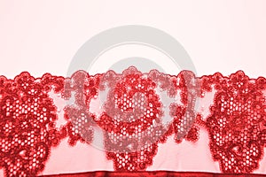 Red lace with a beautiful openwork pattern on a white background. Finishing element for lingerie, clothing photo