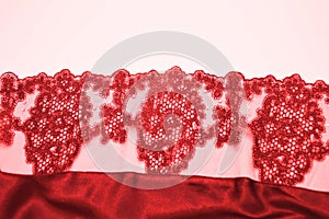 Red lace with an openwork pattern on a white background. Finishing element of lingerie, negligee photo