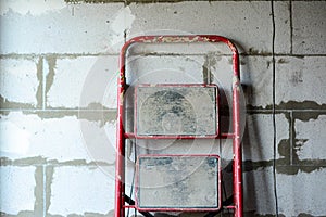 Red ladder on the background of a wall of aerated concrete blocks