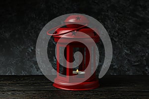 Red lantern on wooden table against black smokey background
