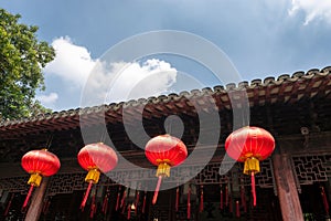 Red lanterns, symbols of vitality and good luck, hanging from the roof of old traditional style Chinese residence