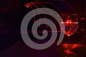 Red laser light painting in a wine glass with bubble water inside