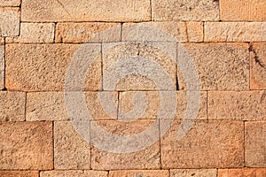 Red laterite stone wall texture background.