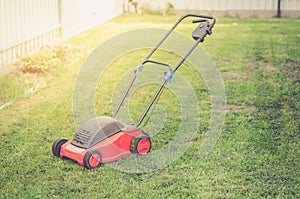 Red Lawn mower cutting green grass/mowing lawn on the grass in the cottage yard