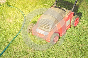 Red Lawn mower cutting green grass/red lawn mower on a green lawn. Selective focus