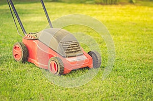 Red lawn mower on a green lawn/red Lawn mower cutting green grass