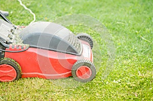 Red lawn mower on the lawn/red lawn mower on the green lawn. Selective focus