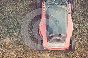 Red lawn mower on the lawn/red lawn mower on the lawn. Toned. Top view