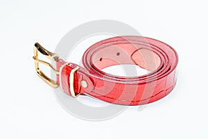 Red leather belt with crocodile texture and golden buckle, isolated on a white background. The belt is neatly folded