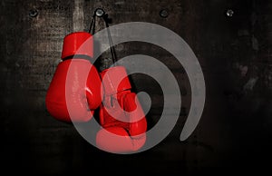 Red leather boxing gloves hanging on black wall