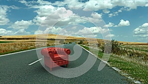 Red leather club armchair on the road