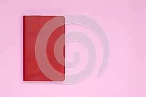 Red leather cover book on pink background with copy space