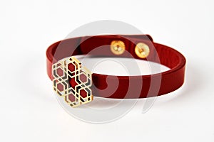 Red leather and gold cuff bracelet on white background with copy space