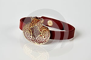 Red leather and gold cuff bracelet on white background with copy space