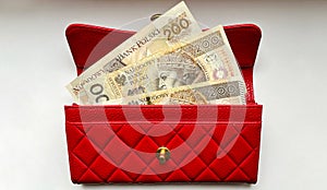 A red leather money wallet with 200 zloty bills in close-up on a white isolated background. Payment in zlotys in Poland