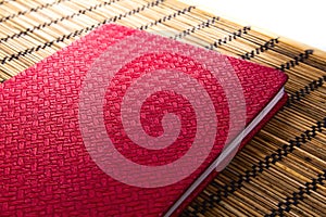 Red leather notebook on bamboo mat