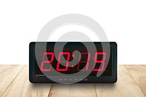 Red led light illumination numbers 2019 on black digital electric alarm clock face on brown wooden table