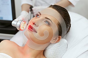 Red Led Light Treatment. Woman Doing Facial Skin Therapy