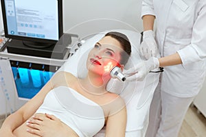 Red Led Light Treatment. Woman Doing Facial Skin Therapy