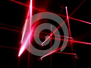 RED LED spotlights with criss-crossing beams lighting an stage in the fog.