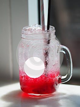 Red lemon soda water flavoured drink, Cool Drinks Beverages with ice in clear glass on white table