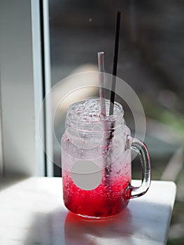 Red lemon soda water flavoured drink, Cool Drinks Beverages with ice in clear glass on white table