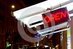 Red len open sign at night on the street. Bright symbol for stores or nightclubs