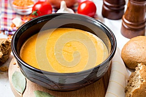 Red lentil cream soup in dark ceramic bowl