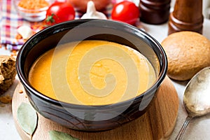 Red lentil cream soup in dark ceramic bowl