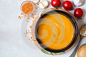 Red lentil cream soup in dark ceramic bowl