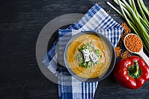 Red lentil cream soup decorated with fresh vegetables and greens. Veggie concept. Proper nutrition. View from above