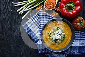 Red lentil cream soup decorated with fresh vegetables and greens. Veggie concept. Proper nutrition. View from above