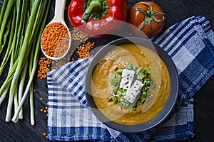 Red lentil cream soup decorated with fresh vegetables and greens. Veggie concept. Proper nutrition. View from above