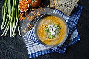 Red lentil cream soup decorated with fresh vegetables and greens. Veggie concept. Proper nutrition. View from above