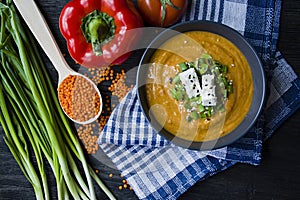 Red lentil cream soup decorated with fresh vegetables and greens. Veggie concept. Proper nutrition. View from above