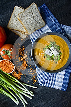 Red lentil cream soup decorated with fresh vegetables and greens. Veggie concept. Proper nutrition. View from above