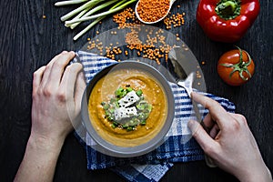 Red lentil cream soup decorated with fresh vegetables and herbs. A man eats soup. Veggie concept. Proper nutrition