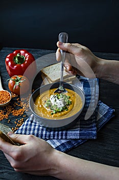 Red lentil cream soup decorated with fresh vegetables and herbs. A man eats soup. Veggie concept. Proper nutrition