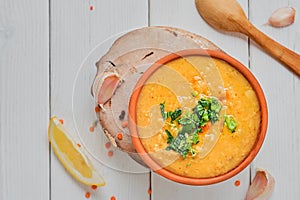 Red lentil soup with ingredients on wooden white plate, top view with copy space. Traditional Turkish or Arabic Lentil Vegetable