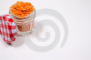 Red lentils in a glass jar, on a white background