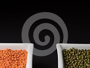 Red lentils and green mung beans on a black background.