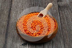 Red lentils in wooden bowl on wooden table background. Top view, copy space. Flat lay