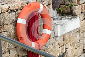 Red Life buoy hanging on stone wall for helping people in a water accident