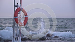 Red life buoy in the stormy winter weather by the Baltic Sea in Helsinki, Finland