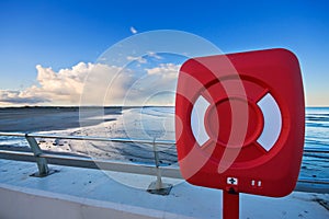 Red life ring by a beach at sunset