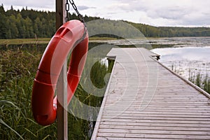 Red life ring buoy hanging from a pole ,next to a pier