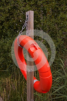 Red life ring buoy hanging from a wooden pole