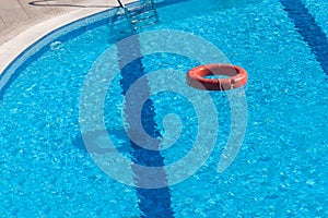 Red lifebuoy floating in hotel pool with beautiful blue water