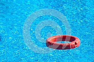 Red lifebuoy floating in hotel pool with beautiful blue water