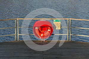 Red lifebuoy hanging on wooden pier, Jordan pond, Tabor, oldest dam in the Czech Republic, sunny autumn day, life insurance